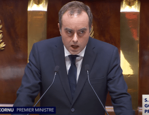 Lecornu in front of two skinny mics, mouth open in mid-speech